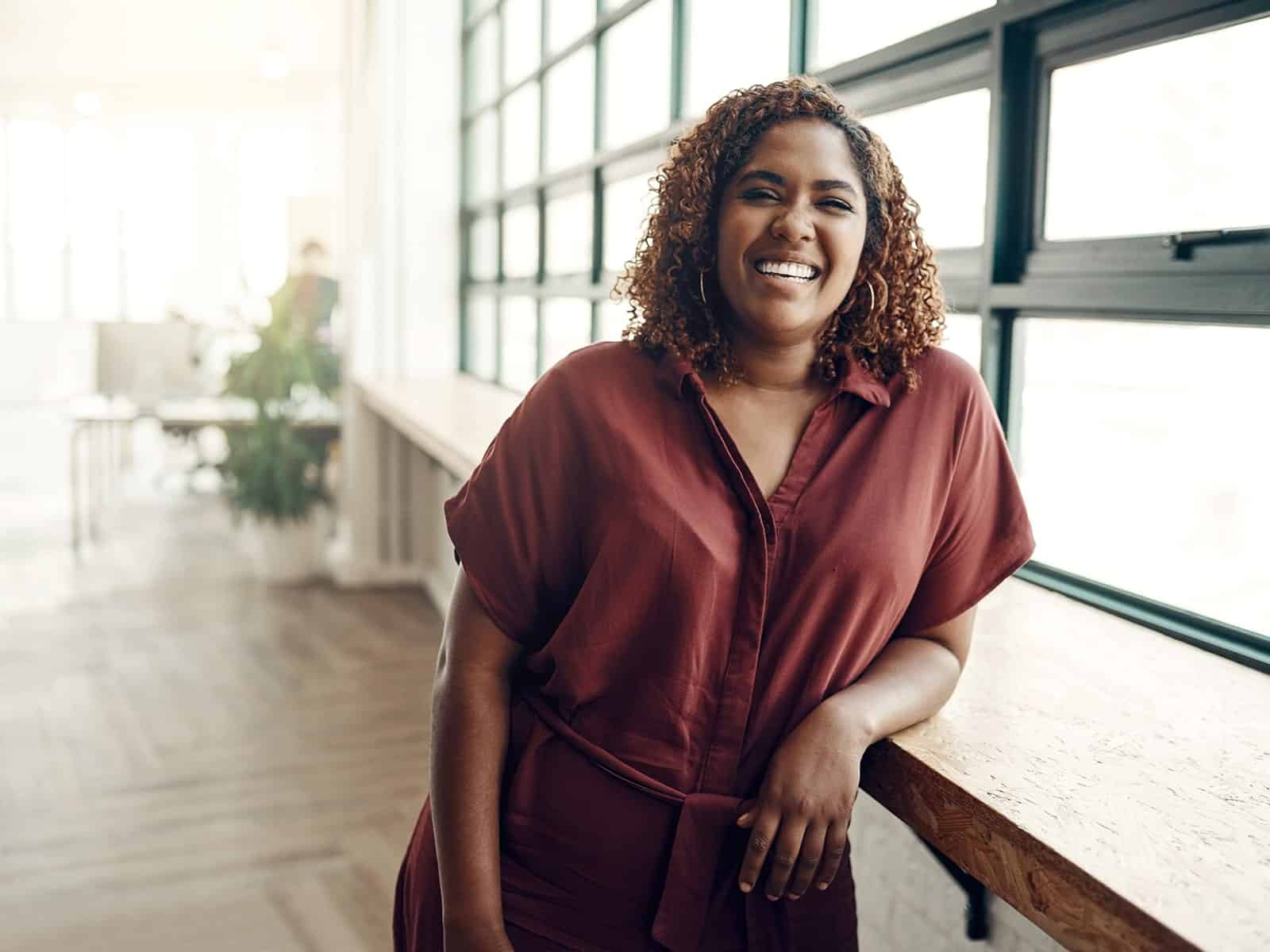 Woman smiling leaning on window ledge
